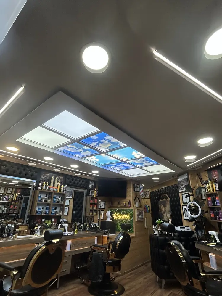 Inside Mercia Barbers under the sky-panel ceiling, gold and black chairs